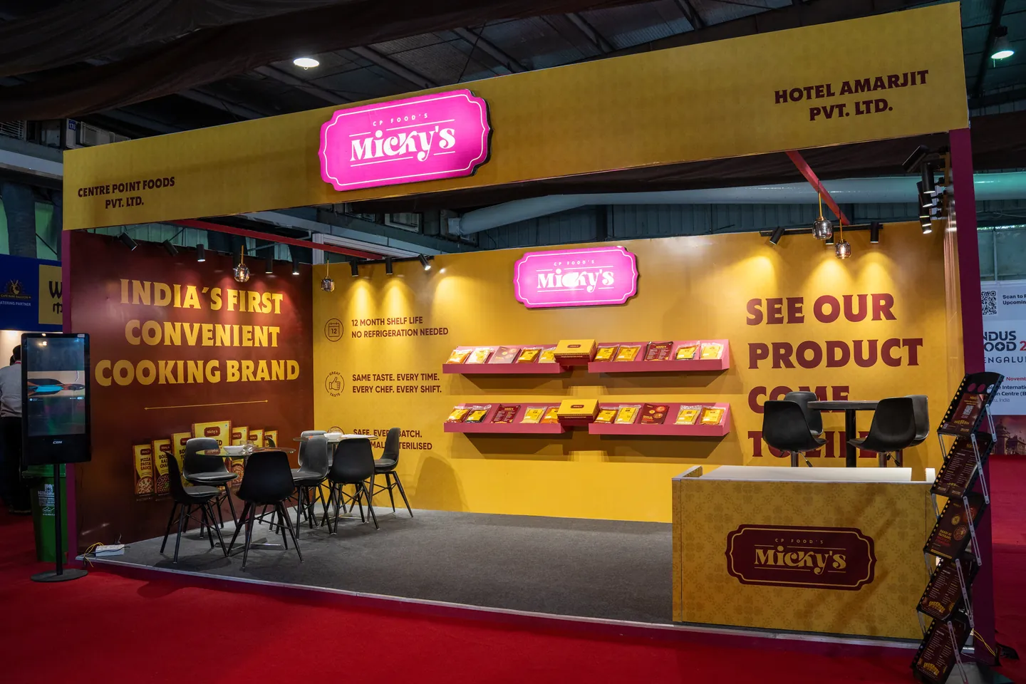 The Micky’s booth at Indus Food Expo 2026: a yellow and maroon stand with the pink Micky’s sign, packs on wall shelves and “India’s first convenient cooking brand” on the side wall