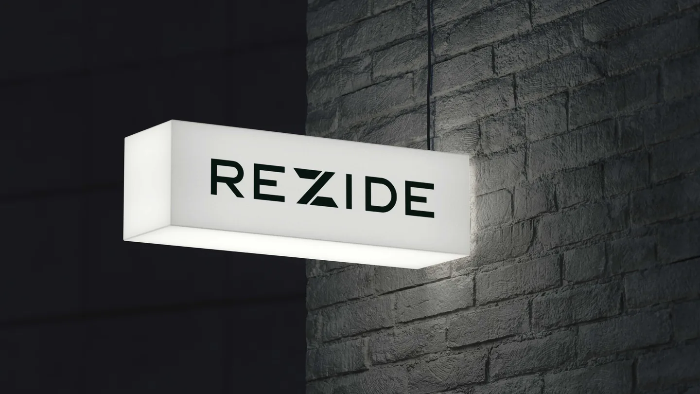 A white Rezide lightbox sign on a dark brick wall